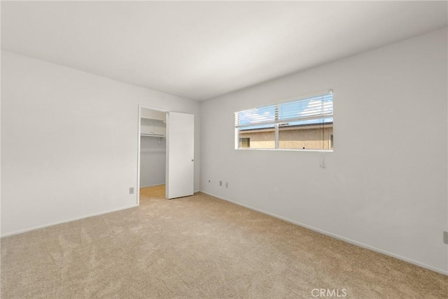 unfurnished bedroom with a spacious closet, light carpet, and a closet