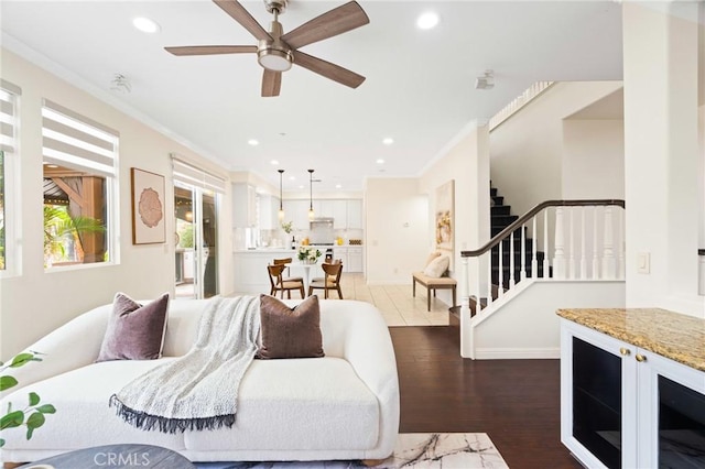 living room with ceiling fan, ornamental molding, and light wood-type flooring