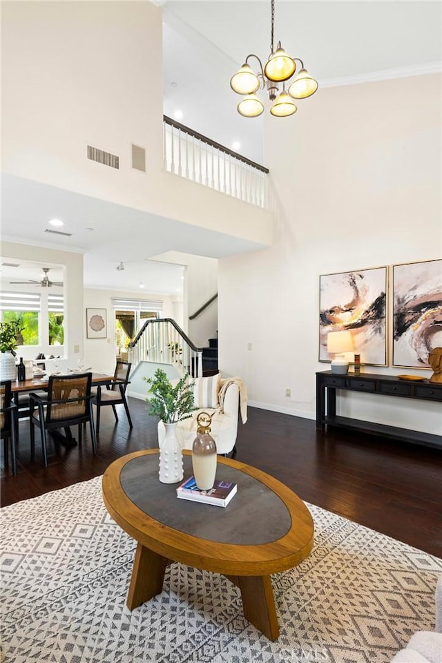 living room with ornamental molding, dark wood-type flooring, and a notable chandelier