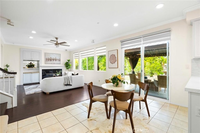 tiled dining area featuring crown molding and ceiling fan