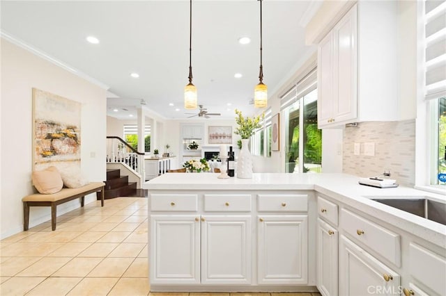 kitchen featuring white cabinetry, ornamental molding, kitchen peninsula, pendant lighting, and backsplash