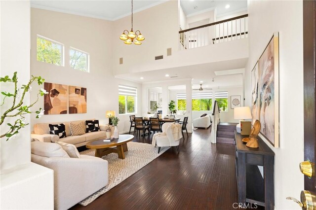 living room with an inviting chandelier, hardwood / wood-style flooring, ornamental molding, and a high ceiling