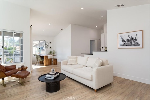 living room with high vaulted ceiling and light hardwood / wood-style floors