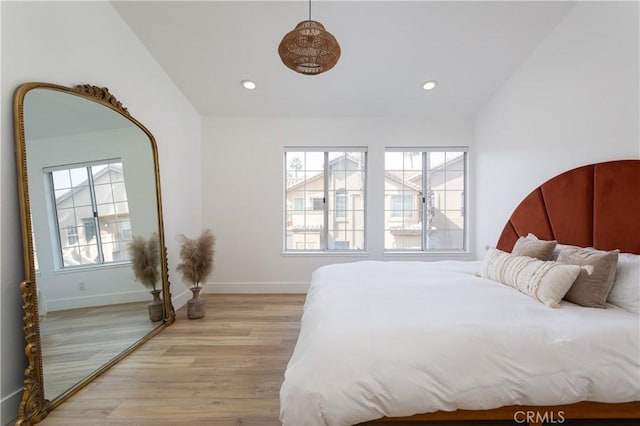 bedroom featuring multiple windows, lofted ceiling, and light hardwood / wood-style flooring