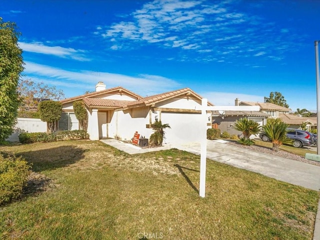 view of front facade featuring driveway, a chimney, a tiled roof, fence, and a front yard