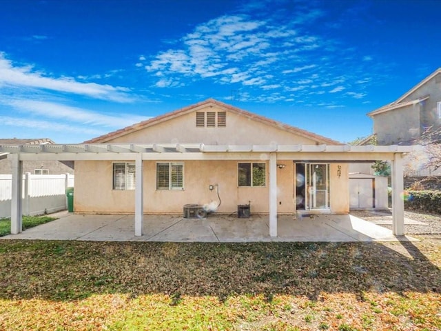 rear view of house featuring an outbuilding, a pergola, fence, and stucco siding