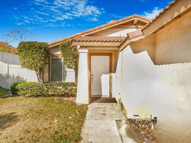 view of exterior entry with fence and stucco siding