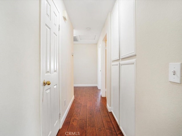 hallway with attic access, baseboards, and dark wood-style flooring