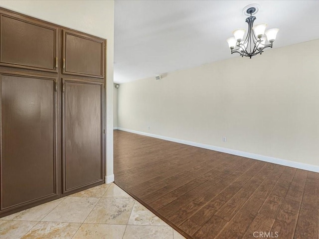 interior space featuring a chandelier, light wood-style floors, and baseboards