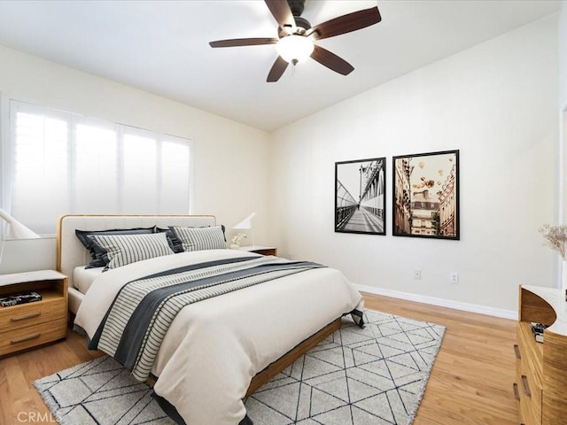 bedroom featuring light wood-type flooring, ceiling fan, baseboards, and vaulted ceiling