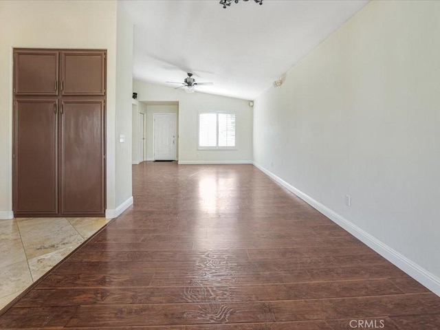 spare room featuring baseboards, a ceiling fan, vaulted ceiling, and wood finished floors