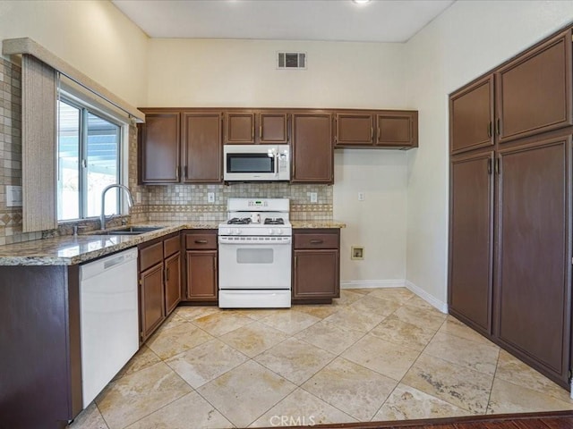 kitchen featuring white appliances, a sink, visible vents, backsplash, and light stone countertops