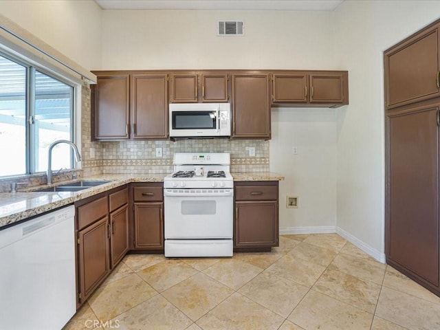 kitchen featuring white appliances, a sink, visible vents, baseboards, and tasteful backsplash