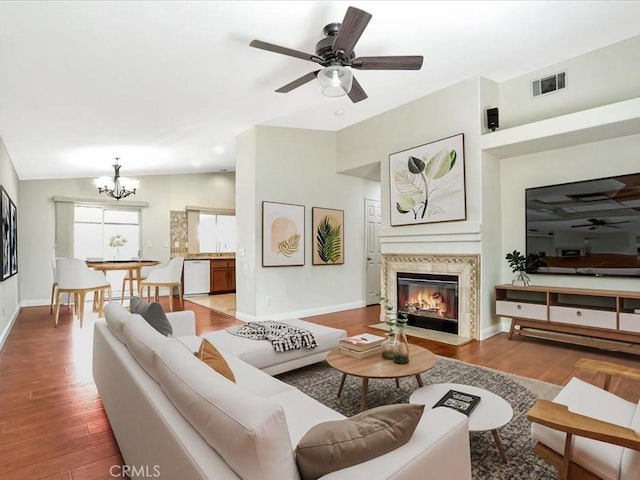 living room with wood-type flooring, lofted ceiling, and ceiling fan with notable chandelier