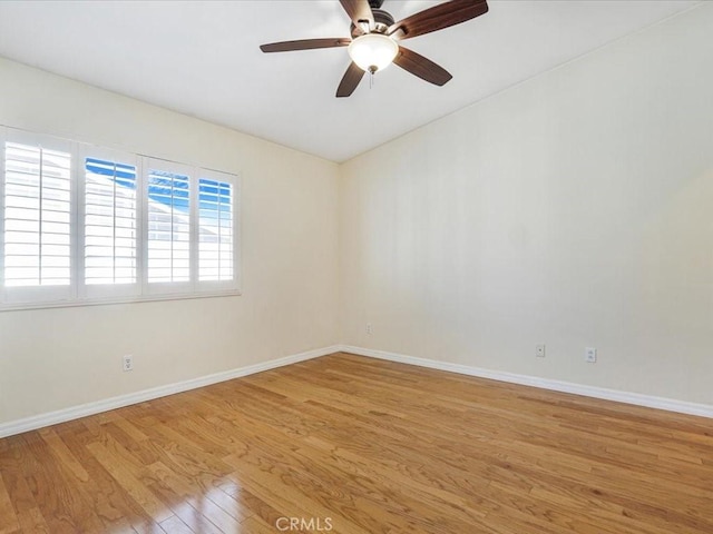 spare room featuring light wood-style floors, lofted ceiling, baseboards, and a ceiling fan