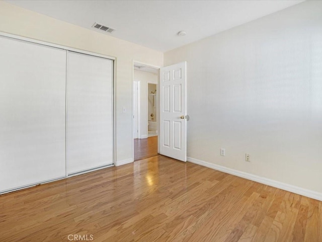 unfurnished bedroom featuring wood finished floors, visible vents, and baseboards