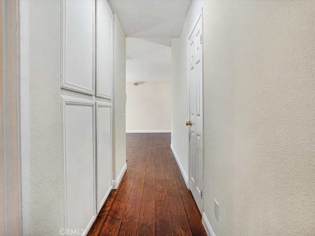 hallway with dark wood-type flooring and baseboards