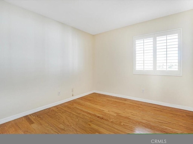 spare room featuring baseboards and wood finished floors