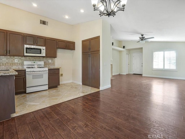 kitchen with light wood-style flooring, white appliances, backsplash, and open floor plan