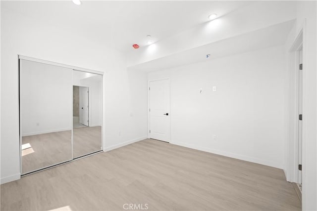 unfurnished bedroom featuring light wood-type flooring and a closet