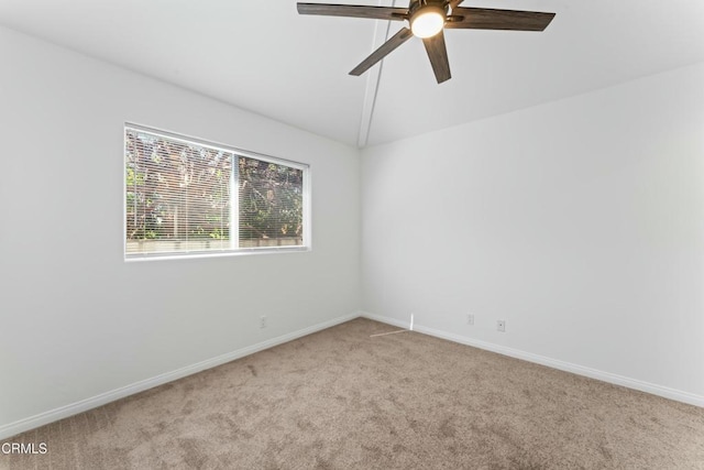 empty room featuring a ceiling fan, light carpet, vaulted ceiling, and baseboards