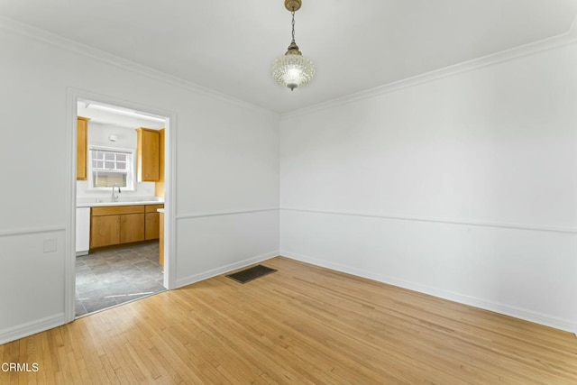 interior space featuring ornamental molding, light wood-type flooring, visible vents, and baseboards