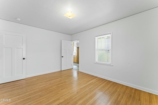 spare room featuring light wood-style floors and baseboards