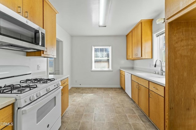 kitchen featuring light tile patterned floors, white appliances, a sink, baseboards, and light countertops