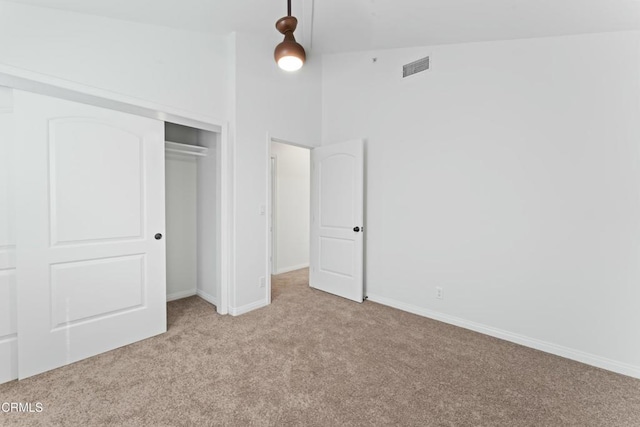 unfurnished bedroom featuring a closet, visible vents, light carpet, high vaulted ceiling, and baseboards