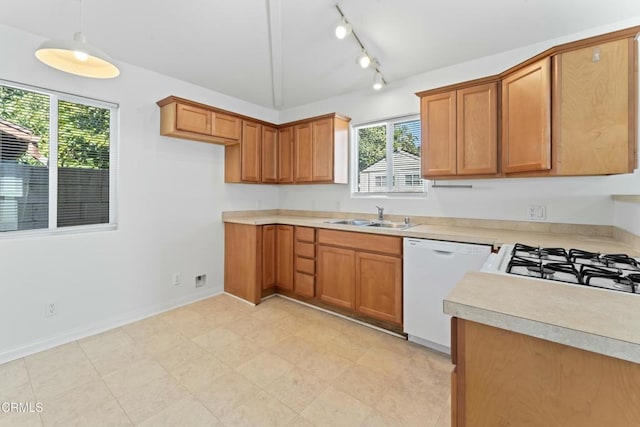 kitchen featuring brown cabinets, light countertops, dishwasher, and a sink