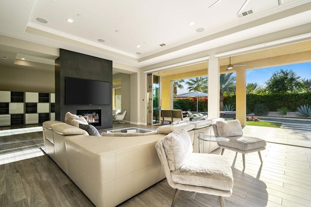 living room featuring wood-type flooring, a fireplace, and a raised ceiling