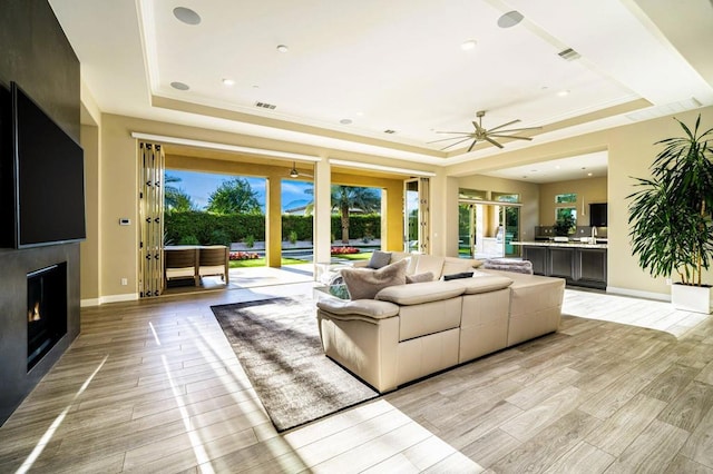 living room with crown molding, a tray ceiling, and light hardwood / wood-style floors