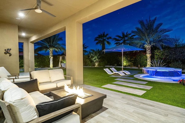 patio at twilight featuring an outdoor living space with a fire pit, ceiling fan, and a lawn