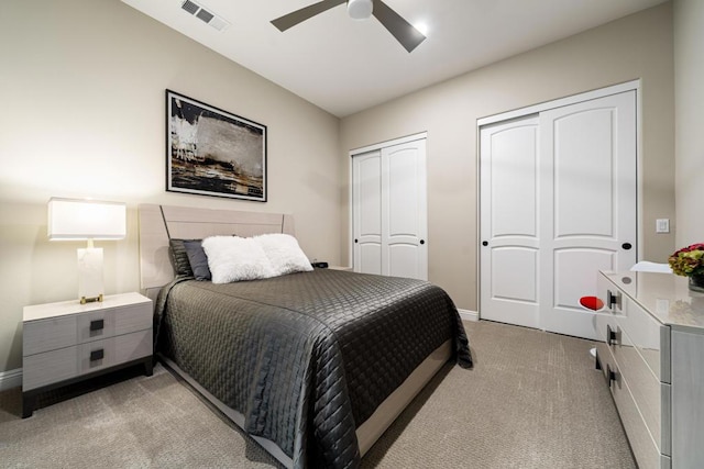 bedroom with multiple closets, light colored carpet, and ceiling fan