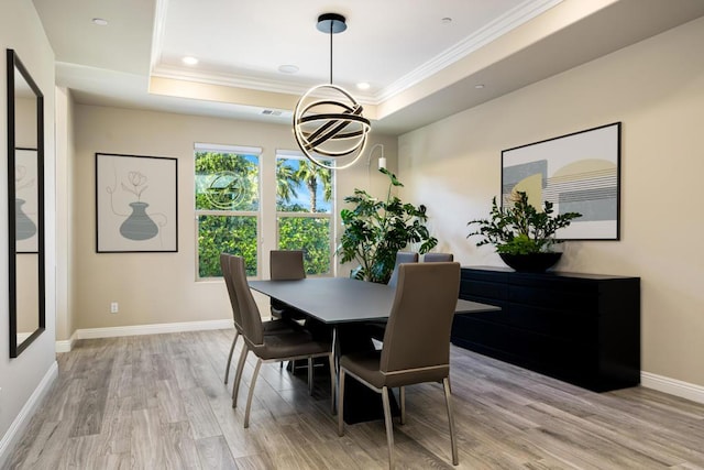 dining area featuring crown molding, a raised ceiling, and light hardwood / wood-style flooring