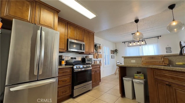 kitchen with decorative light fixtures, sink, light tile patterned floors, stainless steel appliances, and a textured ceiling