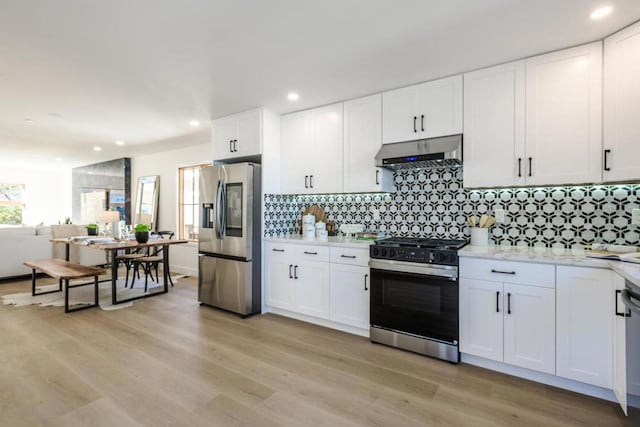 kitchen with stainless steel appliances, extractor fan, tasteful backsplash, and white cabinetry