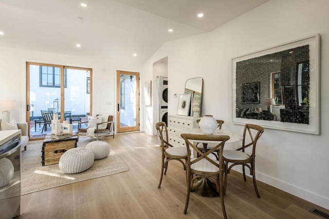 interior space with light hardwood / wood-style flooring, vaulted ceiling, and stacked washing maching and dryer