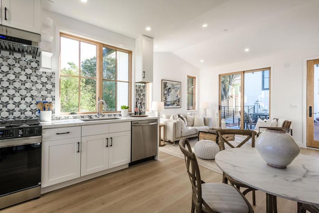 kitchen featuring vaulted ceiling, sink, white cabinets, stainless steel dishwasher, and gas range