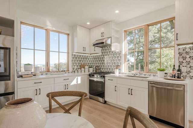 kitchen with appliances with stainless steel finishes, sink, white cabinets, and backsplash