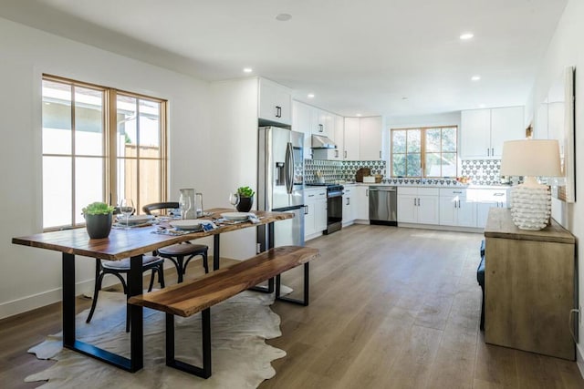 kitchen with stainless steel appliances, white cabinets, light hardwood / wood-style floors, and decorative backsplash