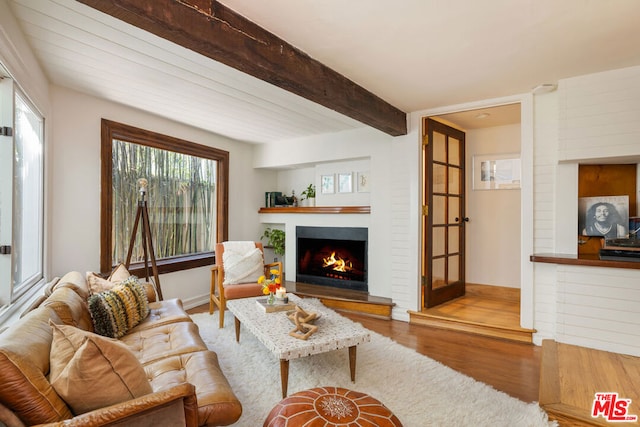 living room featuring beamed ceiling and light hardwood / wood-style floors