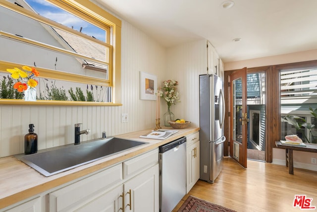 kitchen with white cabinetry, stainless steel appliances, sink, and light hardwood / wood-style flooring