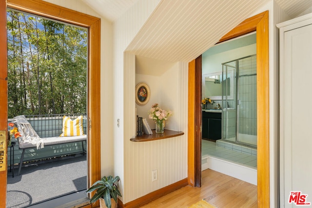 doorway to outside featuring vaulted ceiling and light hardwood / wood-style floors