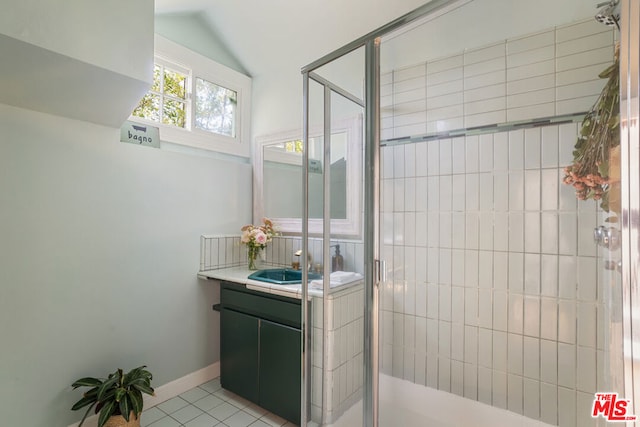 bathroom featuring vanity, vaulted ceiling, tile patterned floors, and walk in shower