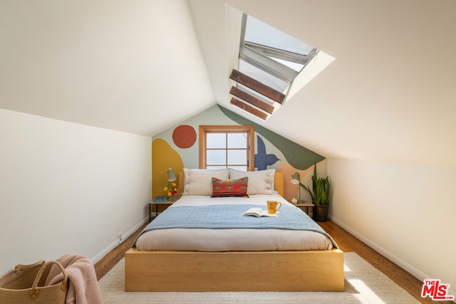 bedroom featuring wood-type flooring and vaulted ceiling with skylight