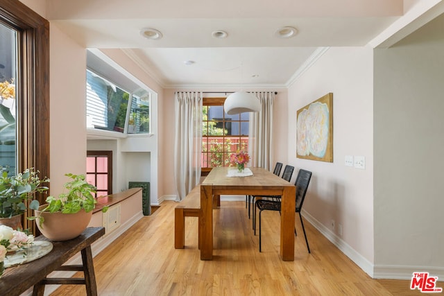 dining room with ornamental molding and light hardwood / wood-style flooring