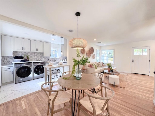 dining room with separate washer and dryer, sink, and light hardwood / wood-style flooring