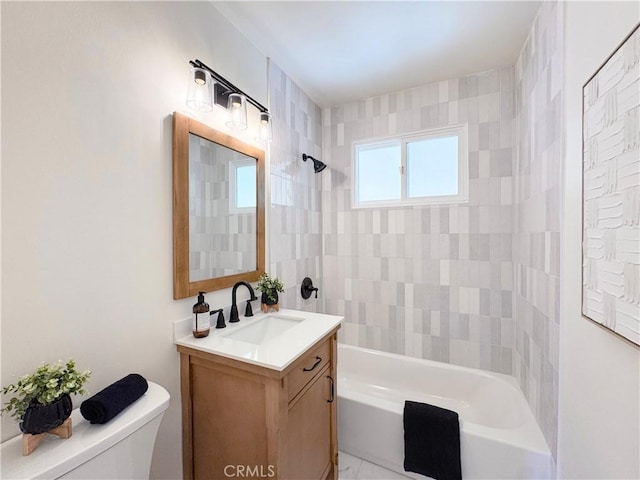 full bathroom featuring vanity, tiled shower / bath, and toilet