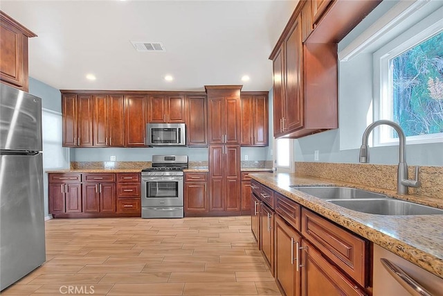 kitchen featuring sink, light stone countertops, and appliances with stainless steel finishes